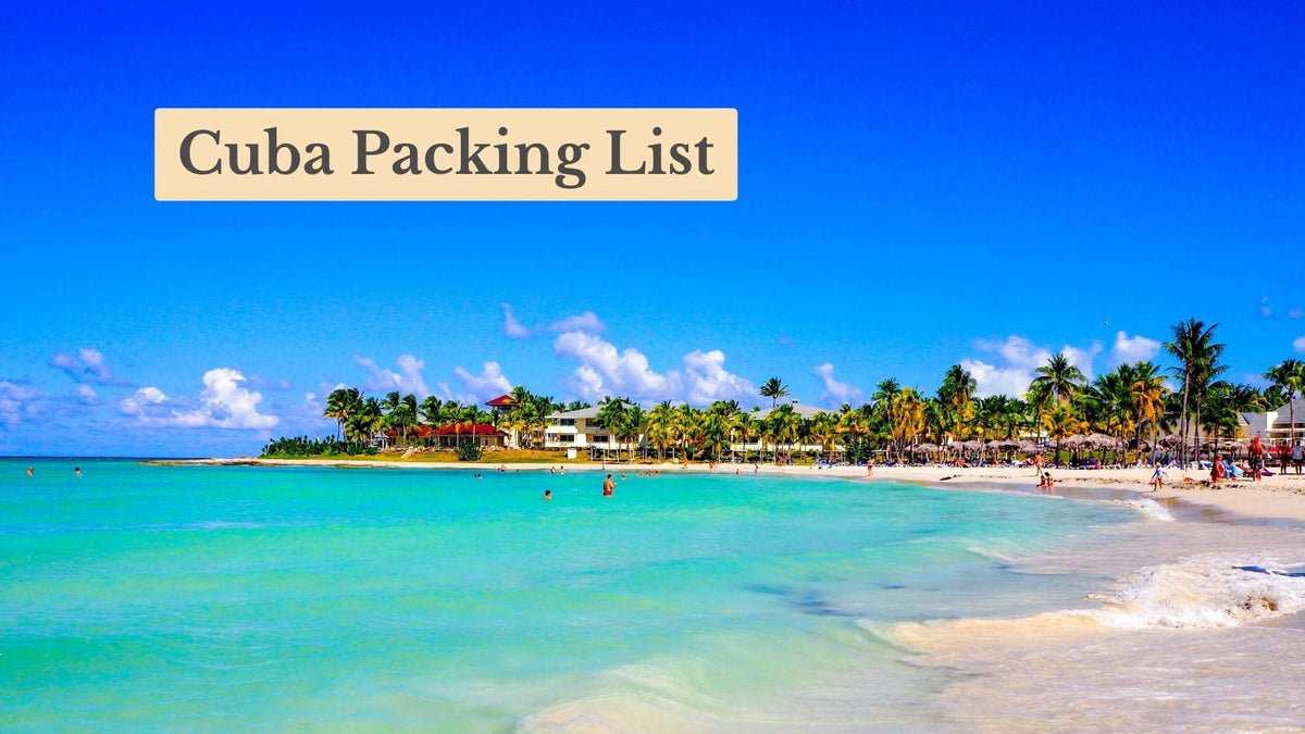 Cuba Packing List title over a turquoise sea and sandy beach lined with palm trees and thatched umbrellas