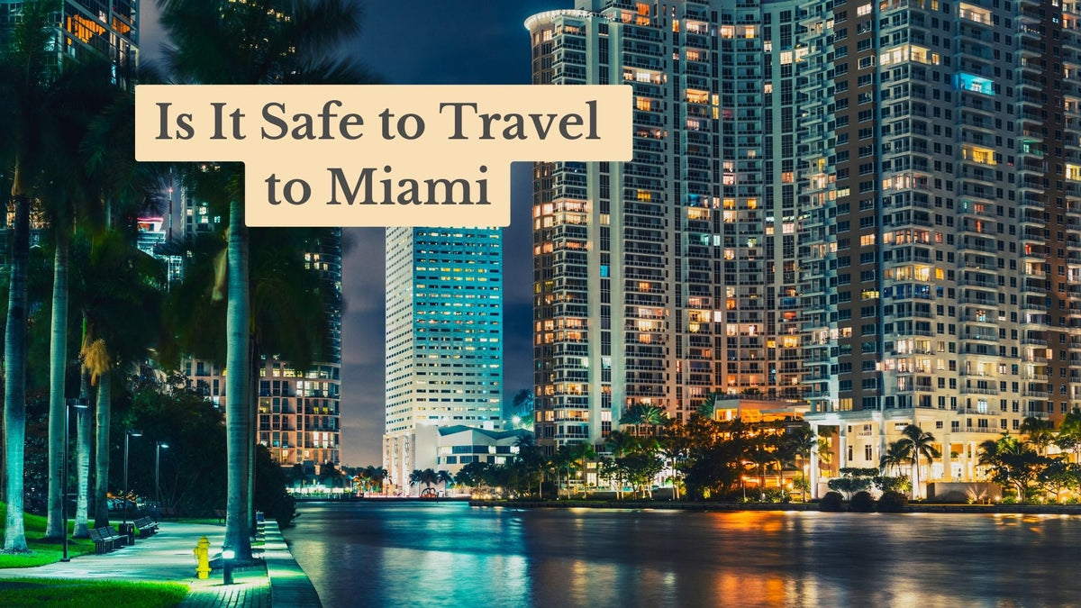 Title card "Is It Safe to Travel to Miami" over a night view of lit high-rises, palm trees and a waterside walkway
