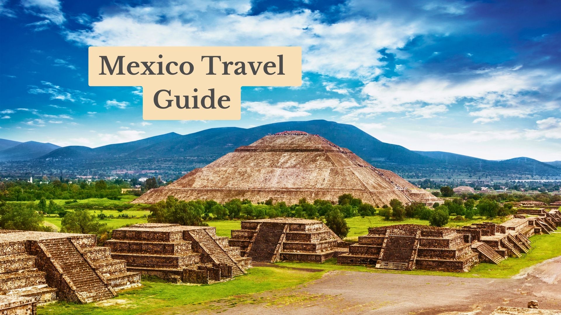 Mexico Travel Guide cover: a large stepped stone pyramid and smaller temple platforms under a blue sky, with mountains behind