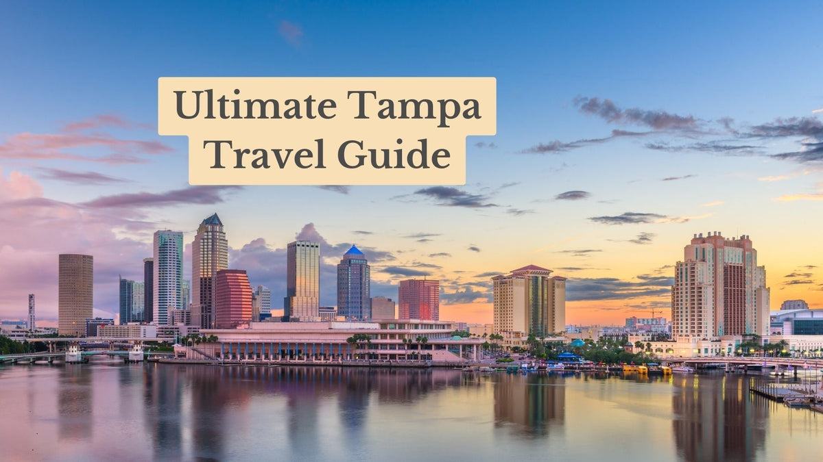 Tampa skyline at sunset with towers reflected in the water, under the title "Ultimate Tampa Travel Guide"