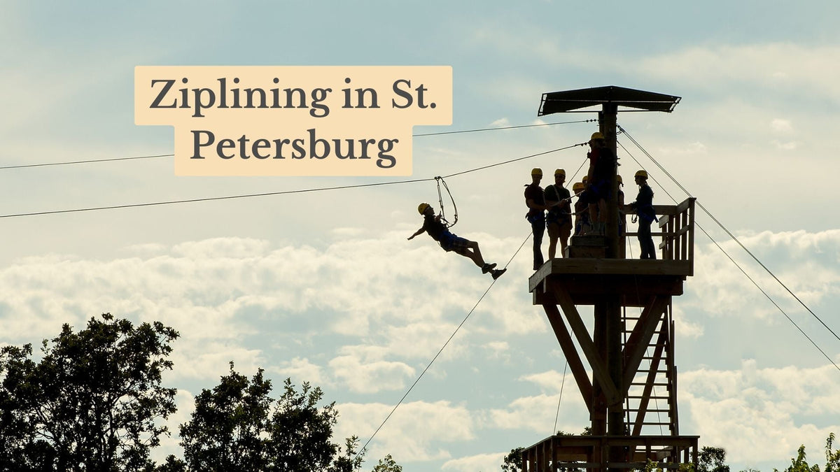 Ziplining in St. Petersburg: a helmeted rider glides off a tall wooden tower where four people wait on the platform.
