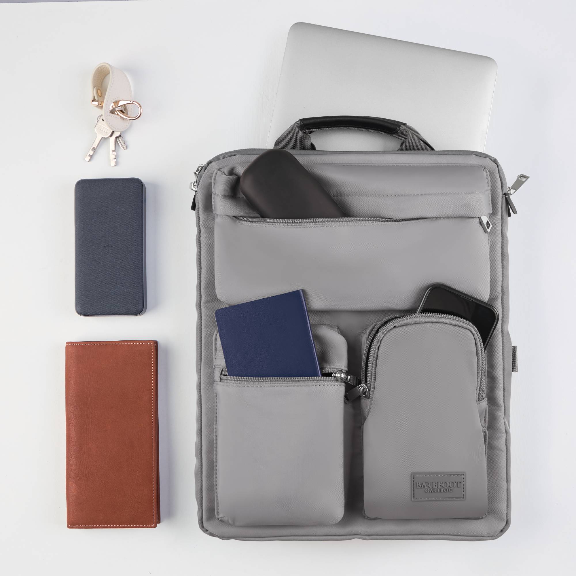 Gray over luggage organizer with compartments containing a phone, wallet, and keys on a white background