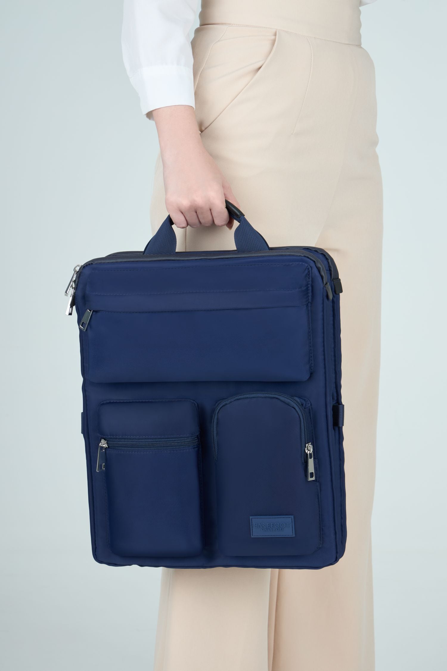 Person holding a navy blue over luggage organizer against a light gray background
